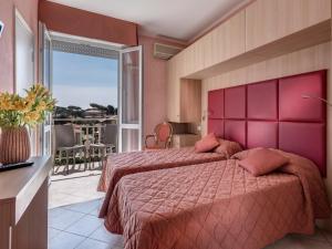 a hotel room with two beds and a balcony at Hotel Azzurra in Marina di Pietrasanta