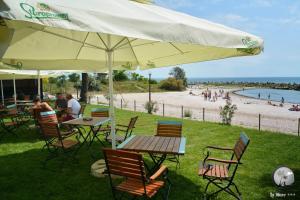 stół i krzesła z parasolem i plażą w obiekcie Bungalouri La Mare*** Saturn w mieście Mangalia