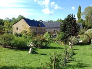ein großes Haus in einem Hof mit Garten in der Unterkunft Gite du Jardin Des Sources in Vaux-sur-Seulles