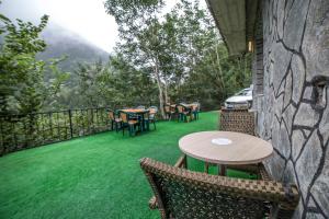 a patio with tables and chairs on a green lawn at Inceli Hotel in Uzungöl