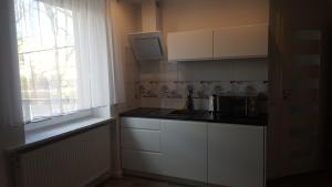 una pequeña cocina con armarios blancos y una ventana en Apartament Centrum 2, en Mikołajki