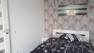 a bedroom with a black and white bed and a wall at Apartament Centrum 2 in Mikołajki