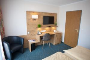 a hotel room with a desk with a tv and a chair at Ruser's Hotel in Schönberg in Holstein