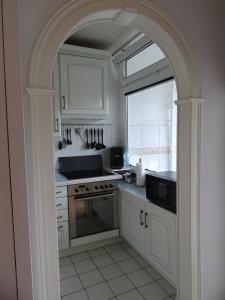 a kitchen with white cabinets and an archway at Ferienwohnung Robbe in Bremerhaven