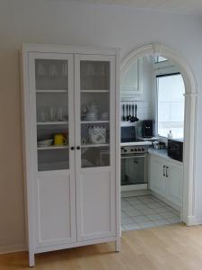 a kitchen with white cabinets and an open door at Ferienwohnung Robbe in Bremerhaven