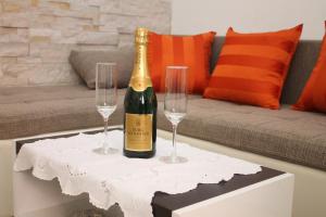 a bottle of champagne and two wine glasses on a table at Apartman Bombon in Selce