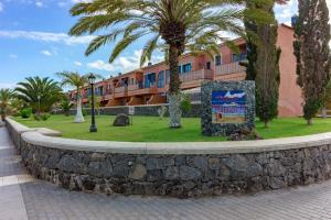 uma parede de retenção em frente a um hotel com palmeiras em Tenerife Montaña Amarilla em Las Galletas