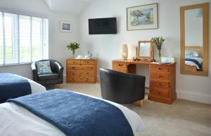 a bedroom with two beds and a dresser and a mirror at Surf Haven in Bude