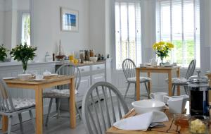 a kitchen with white cabinets and tables and chairs at Surf Haven in Bude