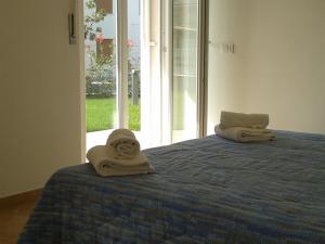 ラツィーゼにあるAppartamento Villa Ivanの窓付きのベッドに座るタオル2枚