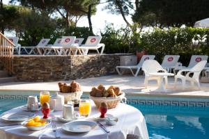 a table with food and drinks next to a swimming pool at Grand Hôtel Du Lido - sur la plage d'Argèles in Argelès-sur-Mer