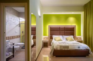 レッチェにあるVilla Domus Salento Suites & Rooms con parcheggio privato in locoの緑の壁、ベッド付きのベッドルーム1室