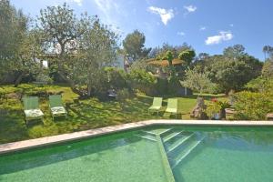 einen Pool in einem Garten mit Stühlen und einem Sonnenschirm in der Unterkunft Villa Spiros in Alcúdia