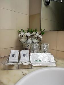 a bathroom sink with towels and a vase of flowers at Apartamentos Turisticos Lindomar in Armação de Pêra