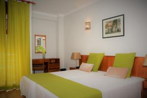 a bedroom with a large bed with green and pink pillows at Apartamentos Turisticos Lindomar in Armação de Pêra