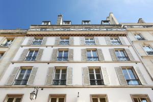 パリにあるPick A Flat's Apartment in Saint Germain - Rue Corneilleの窓とシャッターのある高い白い建物