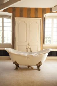 una vasca da bagno bianca in una stanza con finestre di Le domaine de barbizon a Saint-Martin-en-Bière