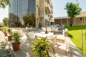 a restaurant with white tables and chairs and plants at MSR Port Hotel in Mangalia