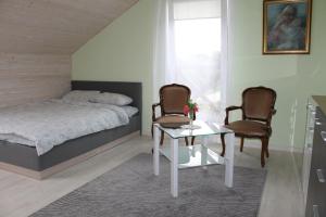 a bedroom with a bed and two chairs and a table at Viesu nams AMRAI in Ventspils