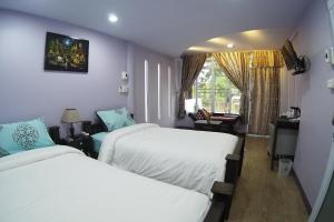 a hotel room with two beds and a window at Pan Din Boutique Guest House in Phra Nakhon Si Ayutthaya