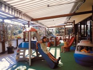 un niño sentado en un tobogán en un parque infantil en Hotel Spiaggia, en Pesaro
