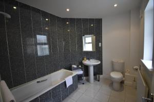 a bathroom with a tub and a sink and a toilet at Aaranmore Lodge Guest House in Portrush +30 photos
