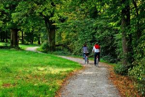 two people riding bikes down a path in a park at Hotel De Dennen in Egmond aan Zee