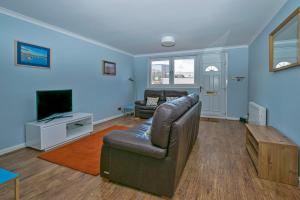 a living room with a couch and a tv at 37A Commerce Street in Lossiemouth