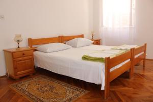 Schlafzimmer mit einem Bett mit weißer Bettwäsche und einem Nachttisch in der Unterkunft Dudić apartmani in Budva