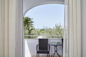 a table and a chair in a room with a window at Mr and Mrs White Corfu Couples Retreat Adults Only in Acharavi