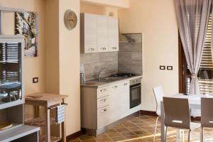 cocina con armarios blancos, mesa y comedor en Casa La Ferula apt2 vicino al mare e Taormina con balcone, en SantʼAlessio Siculo