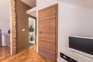 a living room with a television and a wooden door at Apartments Donat in Zadar