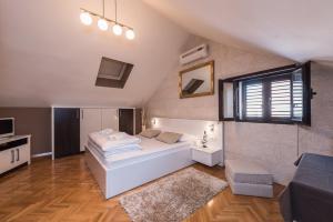 a bedroom with a large white bed and a window at Apartments Donat in Zadar