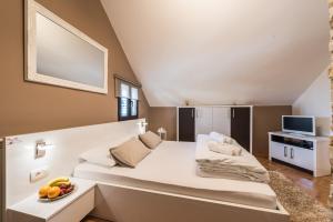 a room with a large white bed with a bowl of fruit at Apartments Donat in Zadar