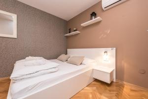 a bedroom with a white bed and a wall with shelves at Apartments Donat in Zadar