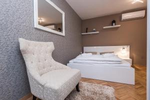 a bedroom with a white bed and a chair at Apartments Donat in Zadar