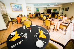 uma sala de jantar com uma mesa preta com guardanapos amarelos em Altamont Court Hotel em Kingston