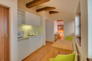 a kitchen with white cabinets and a table and green chairs at 101 PENZION in Prešov