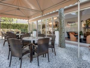 un patio con sillas, mesas y una sombrilla en Hotel Azzurra, en Marina di Pietrasanta
