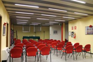 una stanza piena di sedie rosse e un pianoforte di Hotel Griselda a Saluzzo
