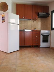 a kitchen with a white refrigerator and wooden cabinets at Casa VeroSol in Castelsardo