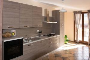 a kitchen with wooden cabinets and a sink and a stove at Casa La Ferula apt3 vicino al mare e Taormina con terrazza panoramica in SantʼAlessio Siculo