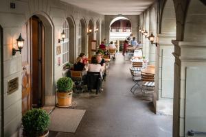 um restaurante com pessoas sentadas em mesas num corredor em Hotel Stadthaus em Burgdorf