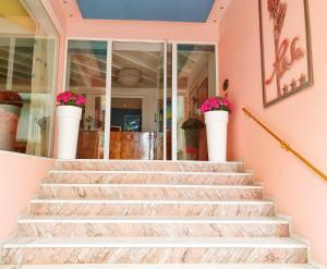 a staircase in a house with pink walls and flowers at Residence Rosa in Gabicce Mare