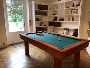 a living room with a pool table in front of a window at La villa rochette in Forges-les-Bains