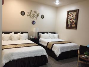 a hotel room with two beds with white sheets at Geyser Inn in West Yellowstone