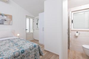 ein weißes Schlafzimmer mit einem Bett und einem Badezimmer in der Unterkunft Apartman Christine in Sreser
