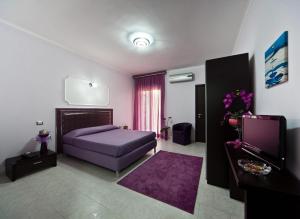 Schlafzimmer mit einem lila Bett und einem Flachbild-TV in der Unterkunft Hotel Glamour in Qualiano