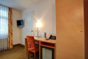 a living room with a desk and a tv at Centro Hotel Nürnberg in Nuremberg