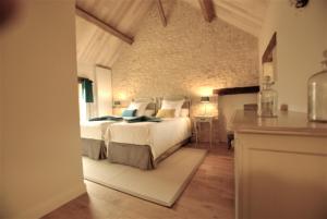 a bedroom with a large bed and a stone wall at Les Maisons du Cheylard-Lascaux in Les Farges